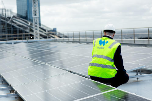 A Walker employee doing maintenance on a solar panel